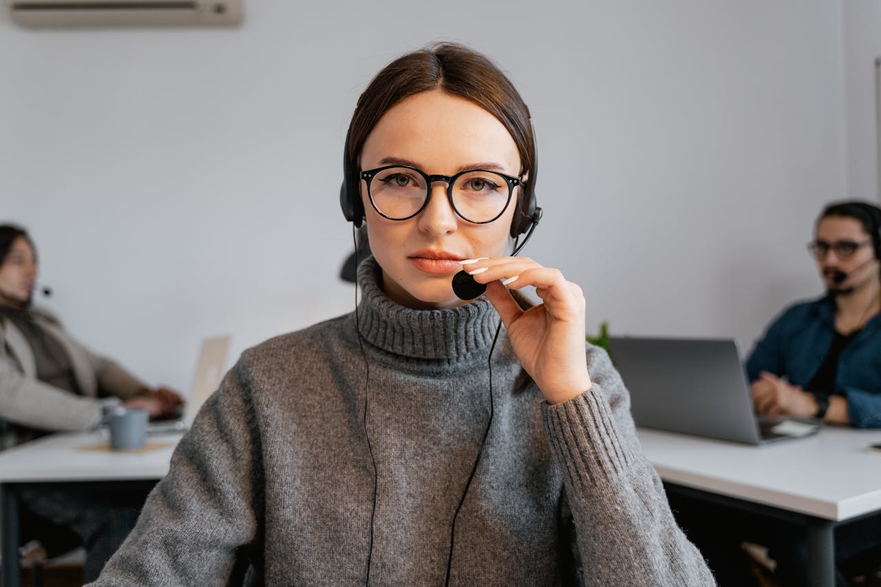 portfolio-01 A focused call center agent with glasses and headset in a modern office setting.